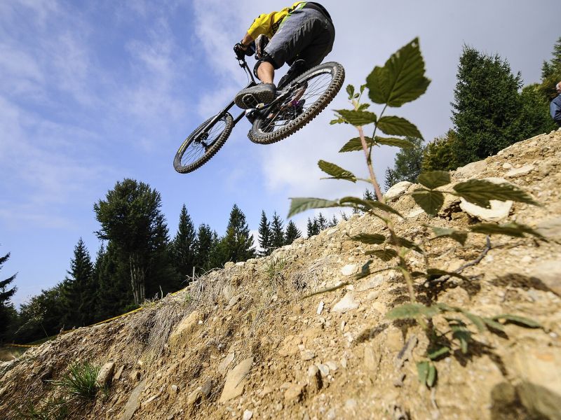Rider springt über eine Felskante, von unten gegen den Himmel fotografiert
