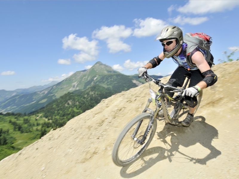 Rider in einer Erdkurve mit Bergpanorama in den Portes du Soleil