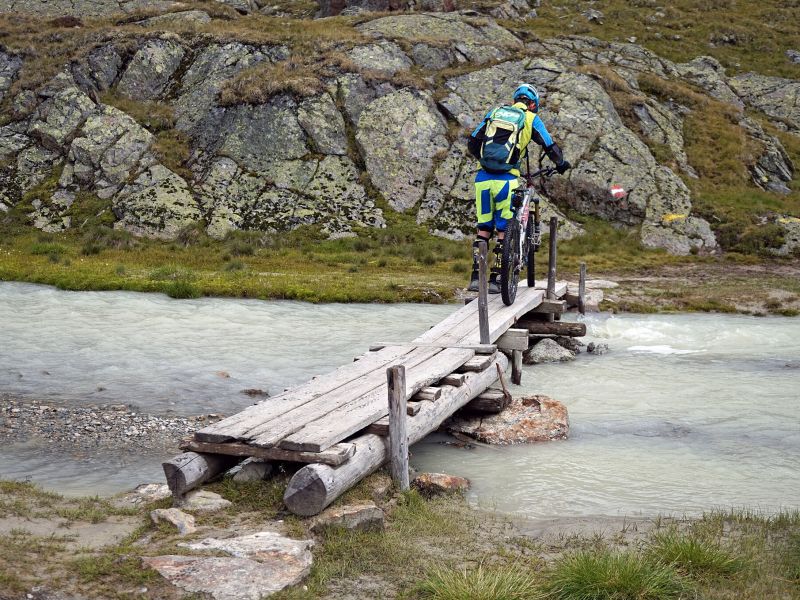 Mountainbiker auf einer Holzbrücke über den Petznerbach bei Sölden
